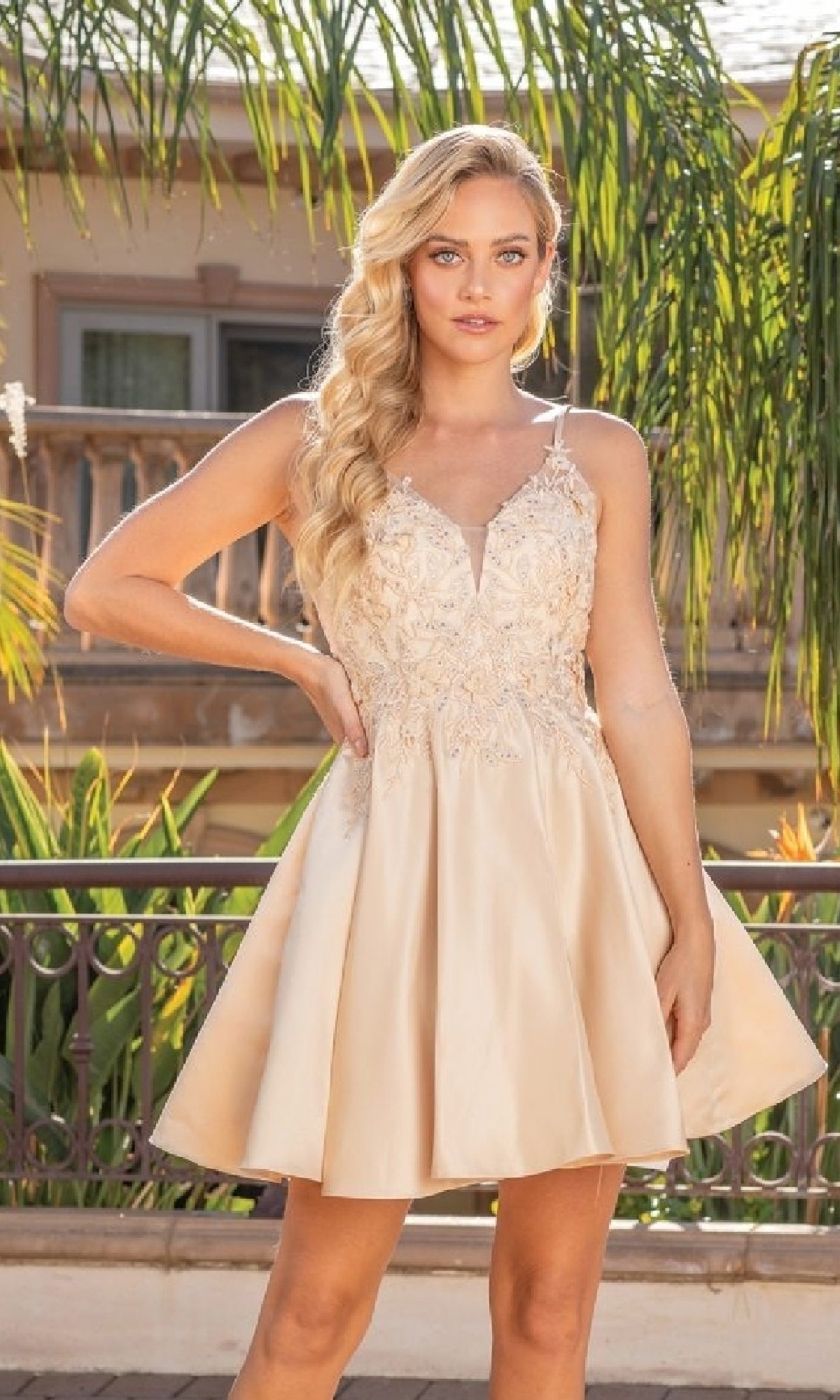 Woman wearing a short champagne dress with floral lace details in an outdoor setting.